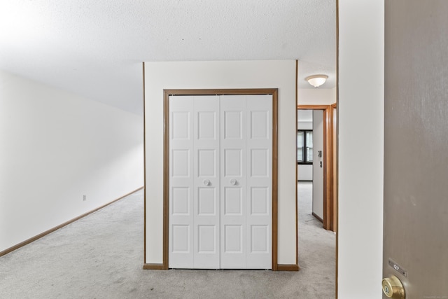 unfurnished bedroom with carpet, a closet, baseboards, and a textured ceiling