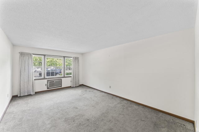 carpeted spare room with a textured ceiling, baseboards, and an AC wall unit