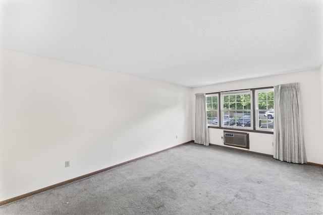 spare room with a wall mounted AC, carpet floors, and baseboards