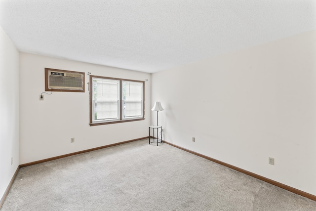 carpeted empty room featuring a wall mounted air conditioner, baseboards, and a textured ceiling