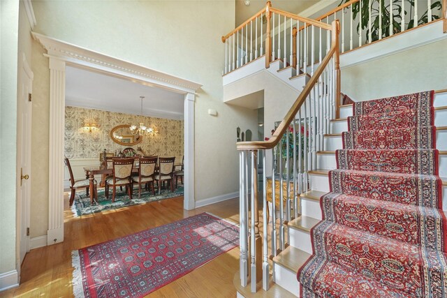 260 Range Rd, Fairfield, CT 06890 - staircase featuring wood finished floors, a chandelier, baseboards, wallpapered walls, and a towering ceiling