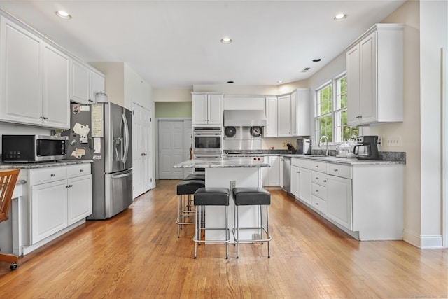 260 Range Rd, Fairfield, CT 06890 - kitchen featuring appliances with stainless steel finishes, white cabinetry, light wood-style flooring, a kitchen breakfast bar, and recessed lighting