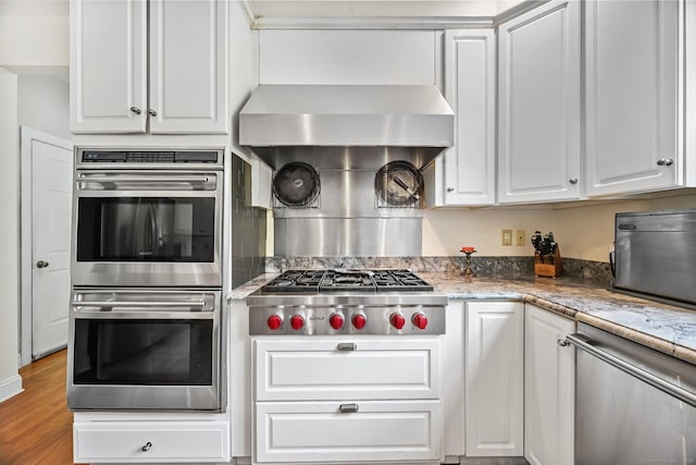 260 Range Rd, Fairfield, CT 06890 - kitchen with appliances with stainless steel finishes, white cabinetry, light wood-type flooring, and light stone counters