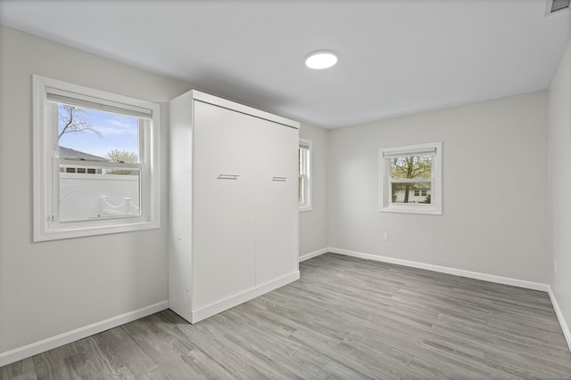 spare room with baseboards and light wood-style flooring