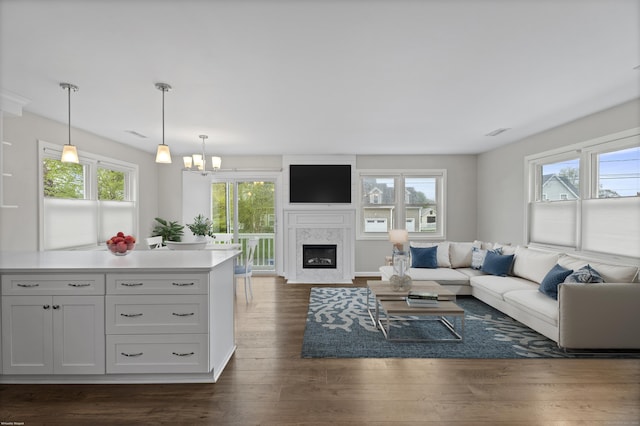 living area featuring a glass covered fireplace, a chandelier, and dark wood-type flooring