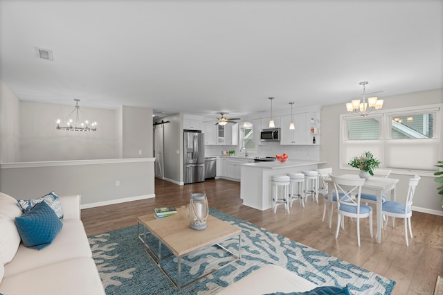 living room with a chandelier, dark wood-type flooring, and baseboards