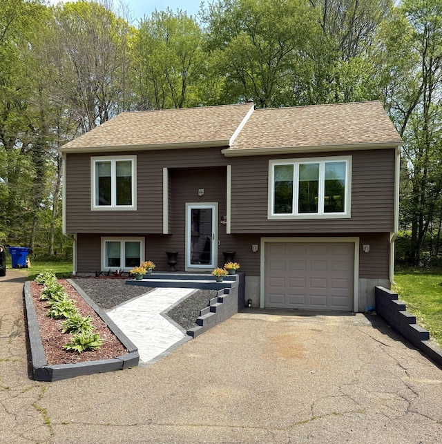 split foyer home featuring aphalt driveway, roof with shingles, and an attached garage