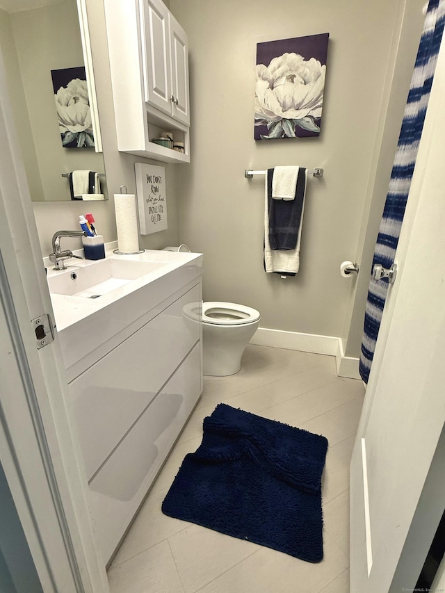 bathroom with vanity, toilet, and baseboards