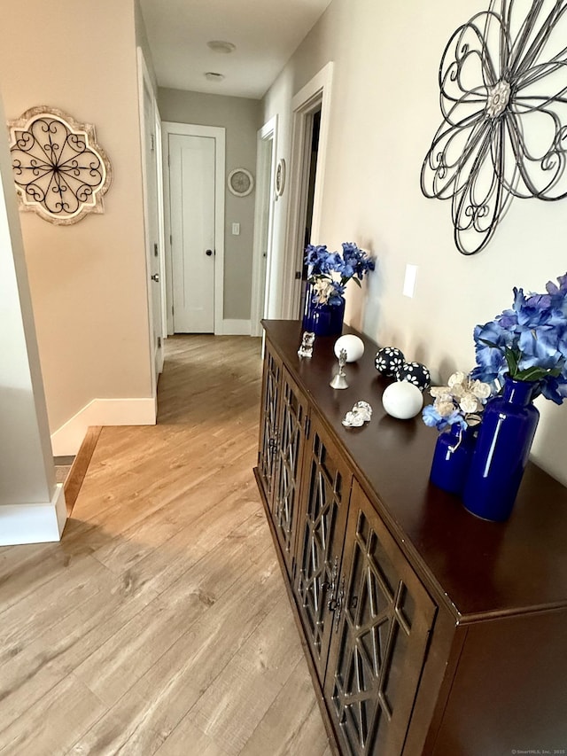 hallway featuring baseboards and light wood-style floors