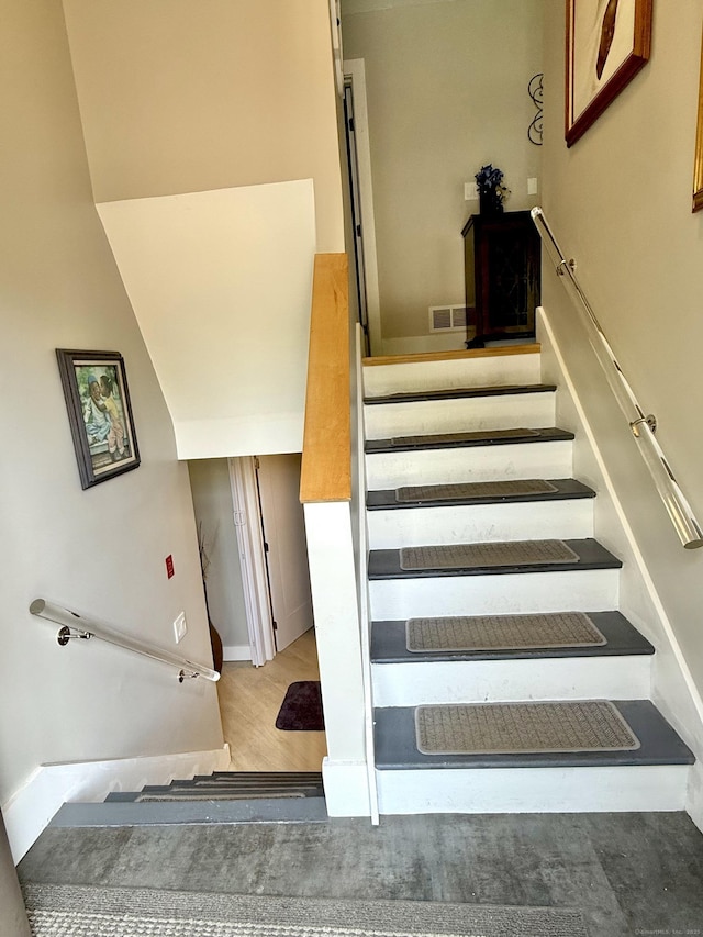 staircase featuring visible vents and wood finished floors