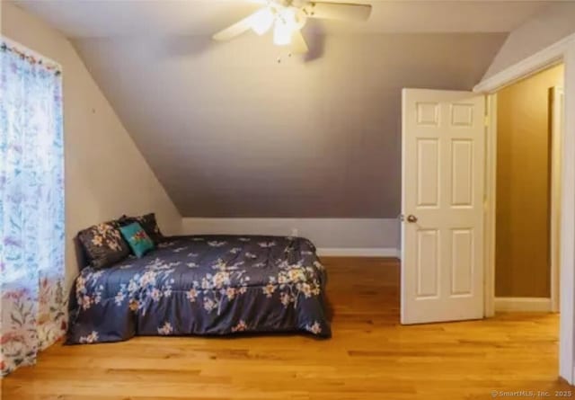bedroom featuring ceiling fan, lofted ceiling, baseboards, and wood finished floors