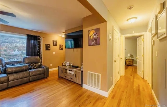 living area with ceiling fan, baseboards, light wood-type flooring, and visible vents