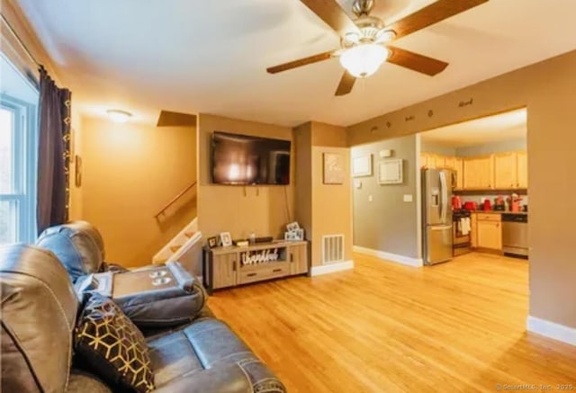 living room with a ceiling fan, baseboards, and light wood-type flooring