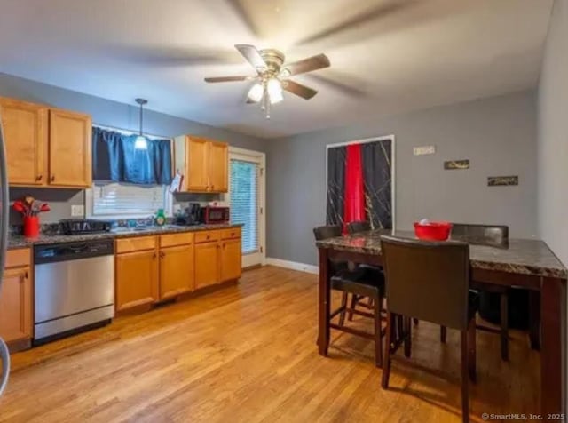 kitchen featuring stainless steel appliances, light wood-style flooring, a ceiling fan, hanging light fixtures, and dark countertops