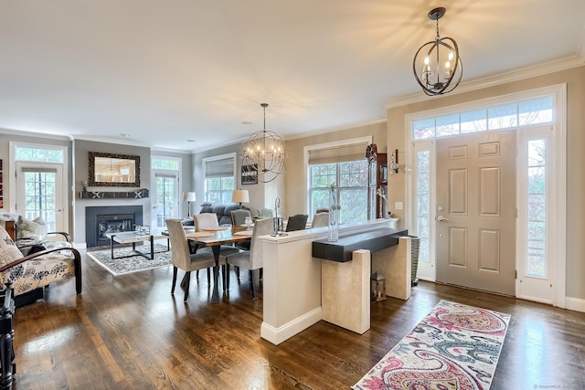 entryway with a chandelier, ornamental molding, a large fireplace, dark wood-style floors, and baseboards