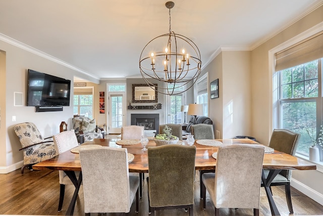 dining room with baseboards, crown molding, dark wood finished floors, a chandelier, and a large fireplace
