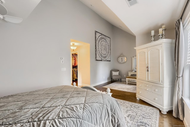 bedroom with high vaulted ceiling, dark wood-style floors, and a walk in closet