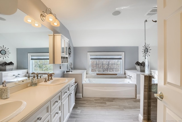 bathroom featuring a bath, double vanity, and vaulted ceiling