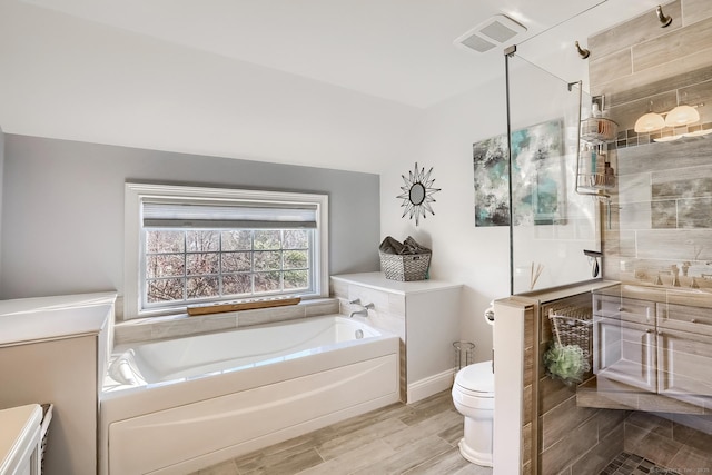 full bathroom featuring a garden tub, tiled shower, toilet, vanity, and lofted ceiling