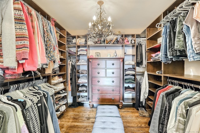 walk in closet with wood finished floors and a chandelier