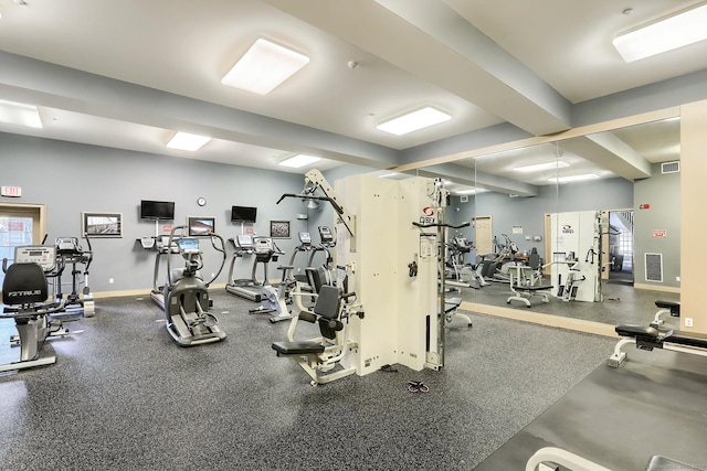 exercise room with baseboards, healthy amount of natural light, and beam ceiling