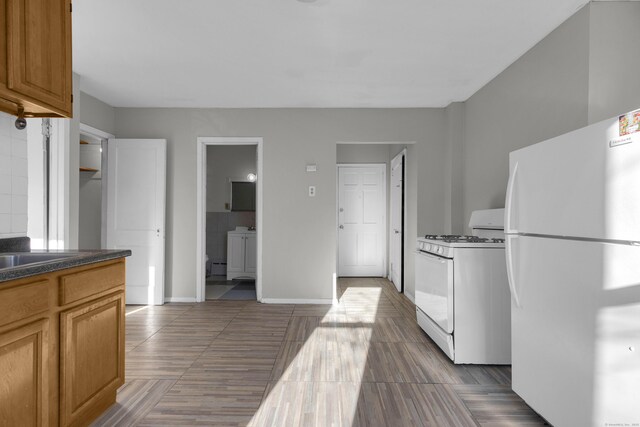 143 Putnam St, Hartford, CT 06106 - kitchen featuring brown cabinetry, white appliances, tile patterned floors, baseboards, and dark countertops