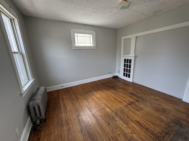 143 Putnam St, Hartford, CT 06106 - empty room featuring radiator, a textured ceiling, dark wood-type flooring, and baseboards