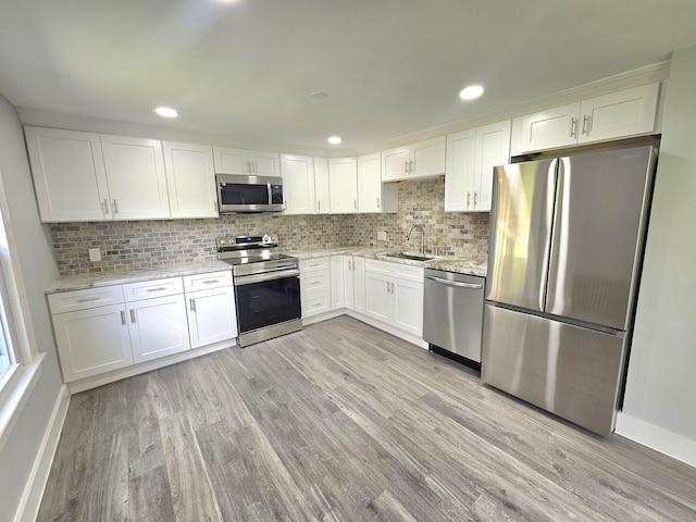 1 Arlington Hts, Norwich, CT 06360 - kitchen with stainless steel appliances, a sink, light wood-style floors, white cabinets, and decorative backsplash