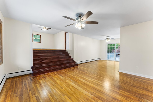 spare room with baseboard heating, hardwood / wood-style flooring, a ceiling fan, and stairway