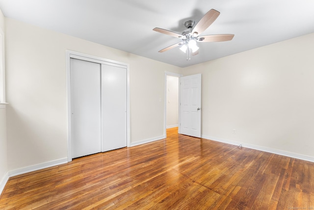 unfurnished bedroom featuring wood-type flooring, baseboards, a closet, and a ceiling fan