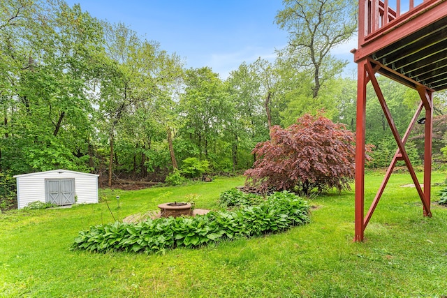 view of grassy yard with an outdoor fire pit, a storage shed, an outdoor structure, and a deck