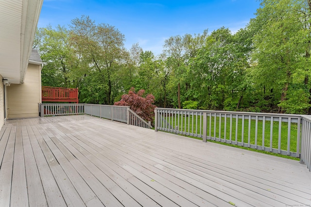 deck featuring a lawn and view of wooded area