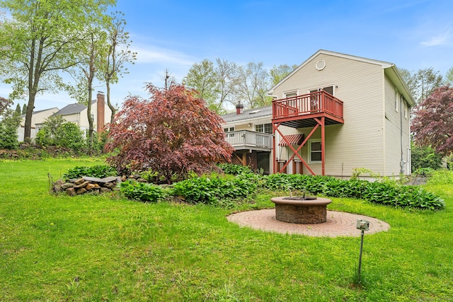 rear view of house featuring a fire pit, a lawn, and a wooden deck