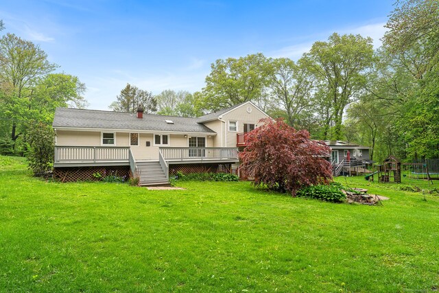 rear view of property featuring a wooden deck, a yard, a playground, and a chimney