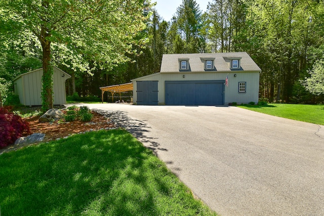 view of front facade featuring an outbuilding, a detached garage, a front lawn, and a shingled roof