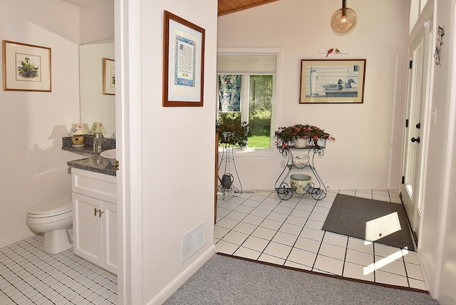 hall featuring light tile patterned flooring and lofted ceiling