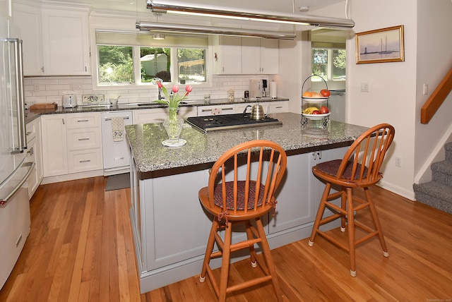 kitchen featuring wood finished floors, a kitchen island, backsplash, and appliances with stainless steel finishes