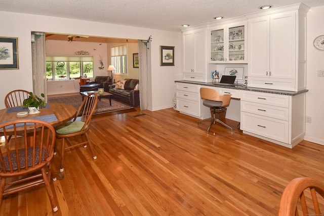 dining room with light wood-type flooring, a textured ceiling, and baseboards