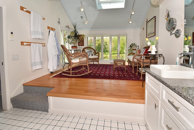 living area featuring lofted ceiling, rail lighting, and a skylight
