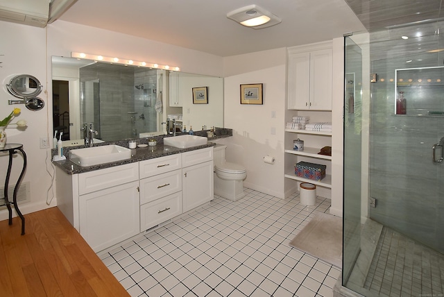 bathroom with a stall shower, double vanity, tile patterned floors, and toilet