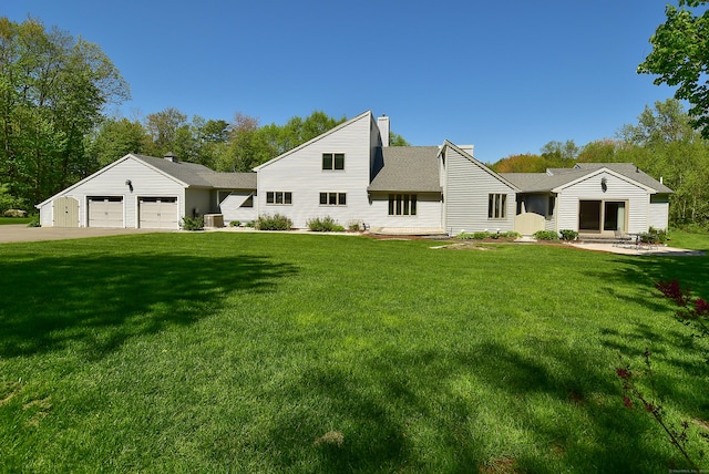 rear view of house featuring a yard, an attached garage, concrete driveway, and cooling unit