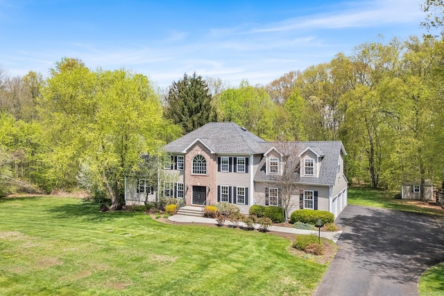 view of front of property with asphalt driveway, a garage, and a front yard