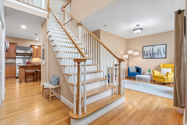 stairs with wood finished floors, baseboards, and recessed lighting