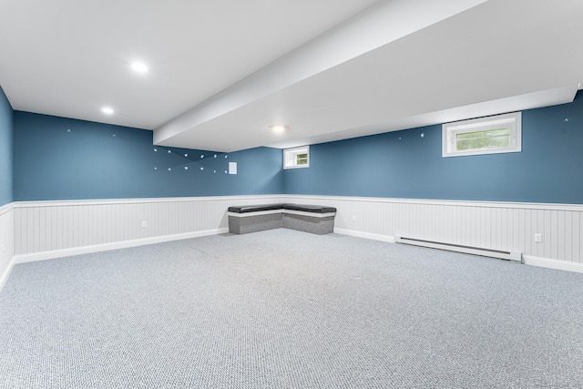below grade area featuring a baseboard heating unit, a wainscoted wall, and carpet
