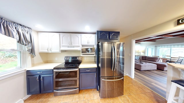 kitchen with appliances with stainless steel finishes, under cabinet range hood, light countertops, blue cabinetry, and recessed lighting