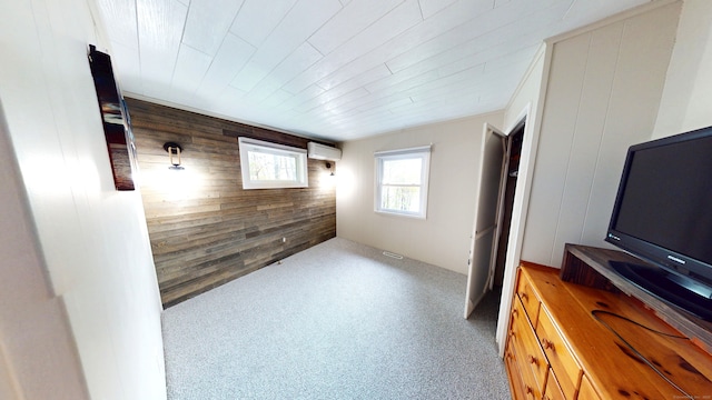 unfurnished living room with an AC wall unit, wood walls, and carpet floors
