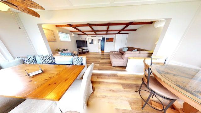 dining space featuring coffered ceiling, light wood-type flooring, and beamed ceiling
