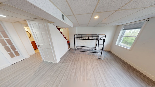 unfurnished bedroom featuring a drop ceiling, baseboards, wood finished floors, and recessed lighting