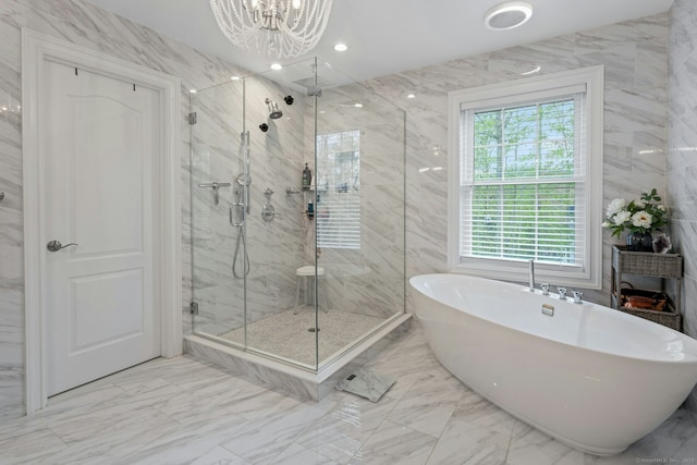 bathroom with a soaking tub, a marble finish shower, marble finish floor, and a notable chandelier