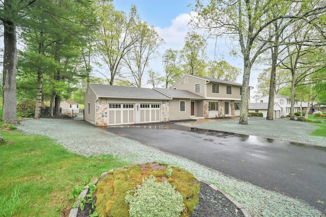 view of front of house featuring stone siding, an attached garage, asphalt driveway, and fence